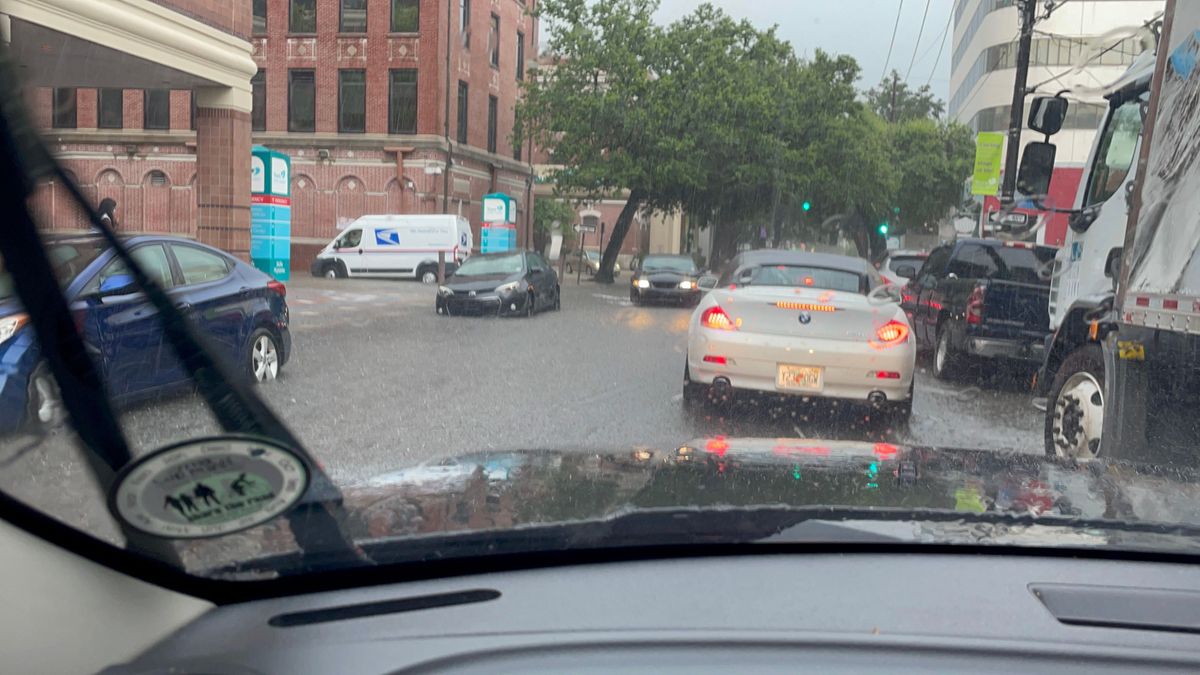 Photo of a flooded street and a mail van driving.